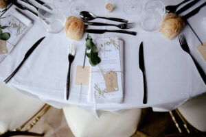 table préparée avec couverts et petits pains, décorée avec menu et branche de plante