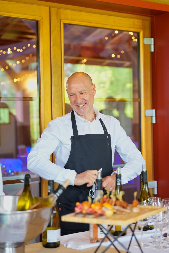 homme sommelier qui sourit en ouvrant une bouteille